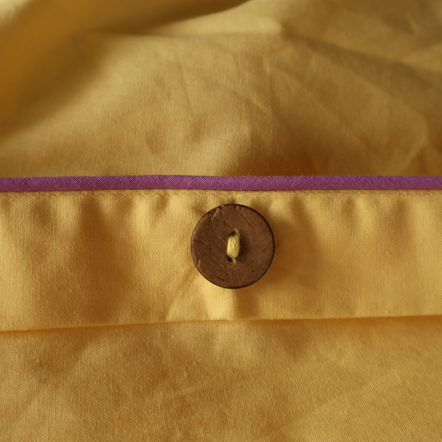 Close-up of natural coconut buttons on a BUTTIA duvet cover made of organic fabric.