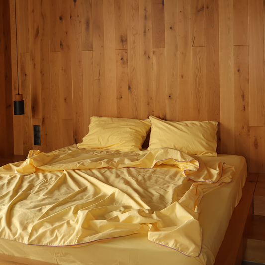 Complete yellow bedding collection by BUTTIA including a soft bed sheet, pillowcases and a duvet cover with lavender piping.