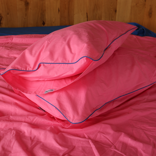 Pink sleeping bag with blue stitching on a wooden background