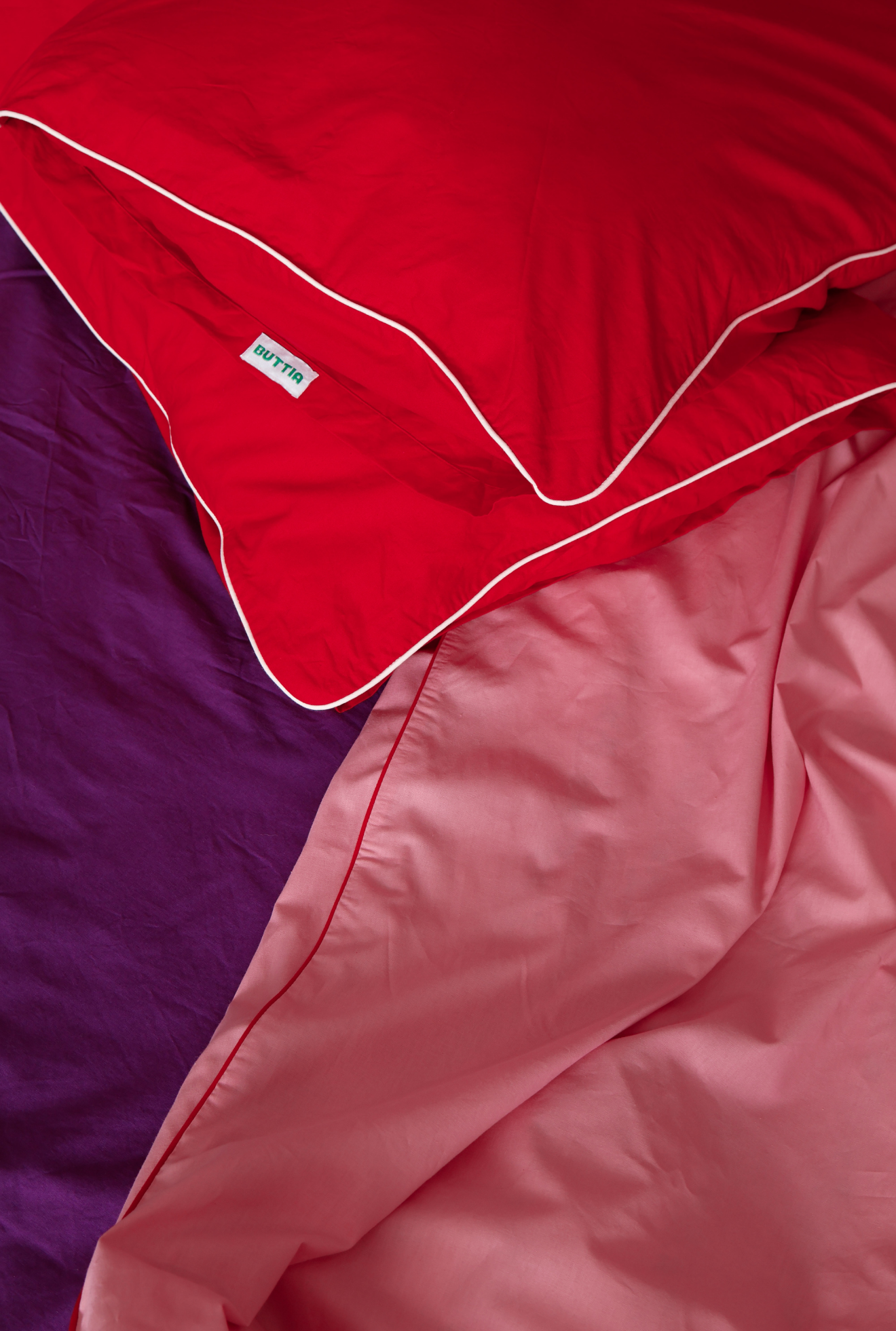 Red quilt with white trim on a purple and pink background