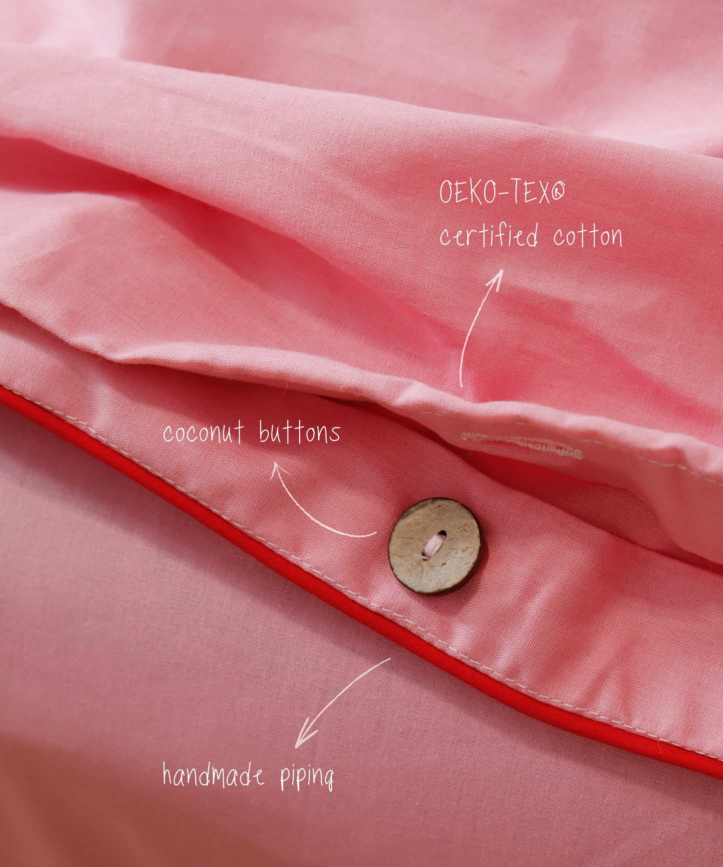 Close-up of pink fabric with coconut button and red piping, featuring OEKO-TEX certified cotton text.