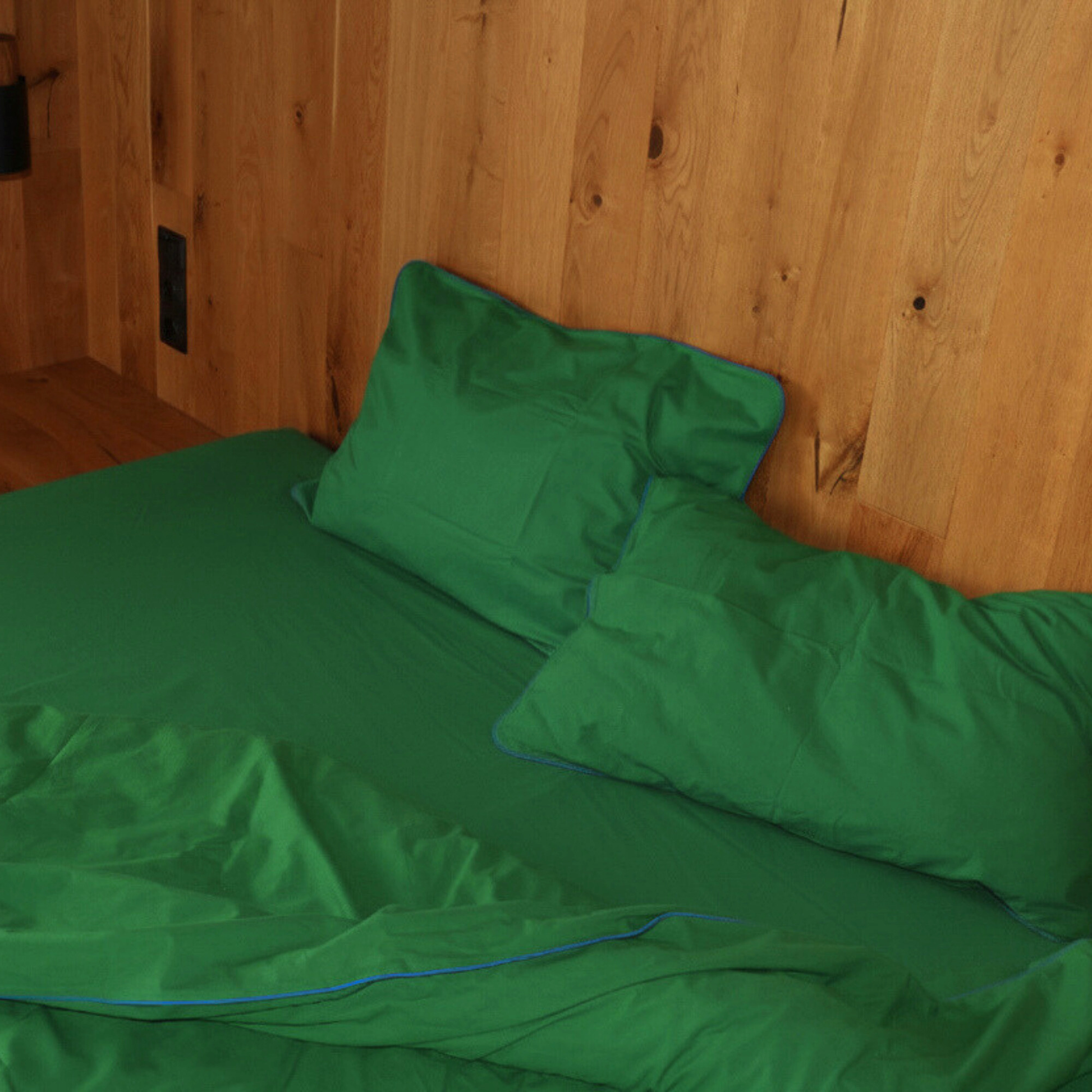 Green bedsheets from BUTTIA with elegant blue piping details, made of high quality natural cotton fabric.