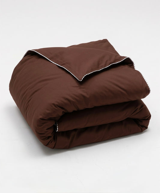A folded brown quilted comforter with white contrast stitching along the edge, displayed on a clean white background.