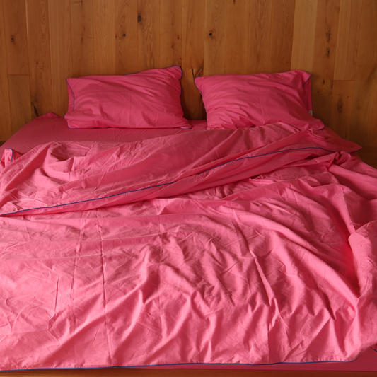 Pink bedspread and pillows on a wooden bed