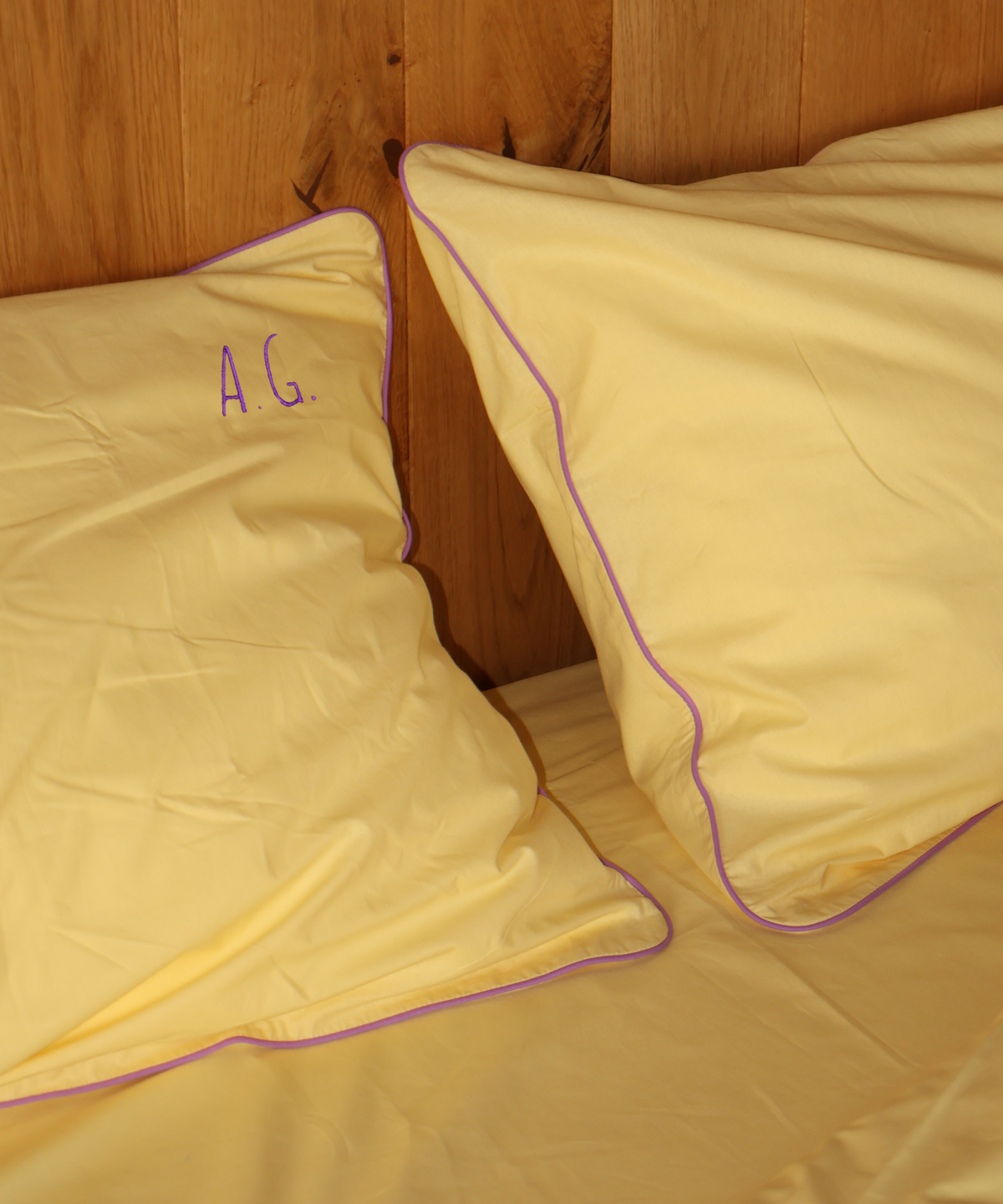 Yellow pillowcases with purple piping trim and a purple monogram 'A.G.