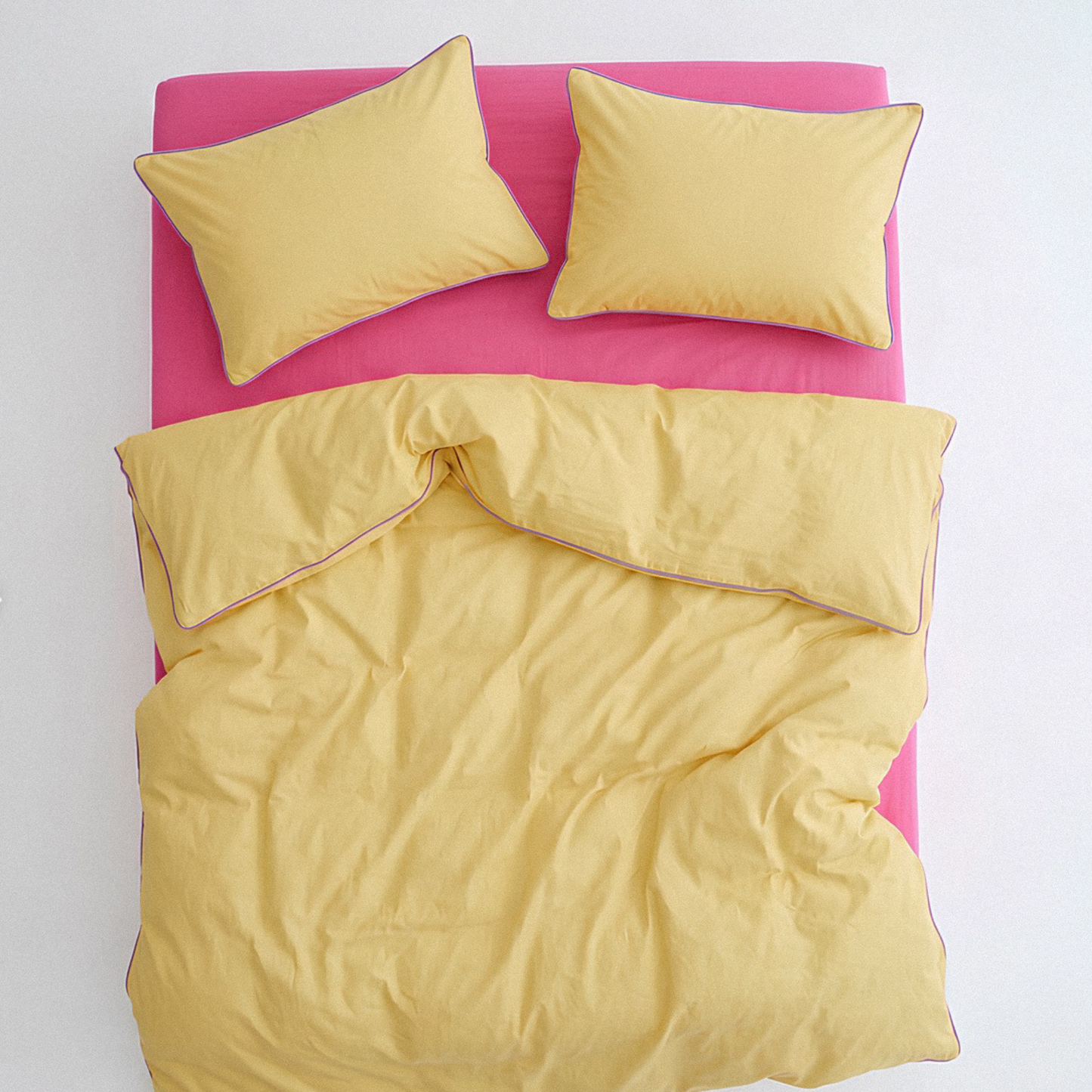 Yellow bedding set with pink bed frame on a white background