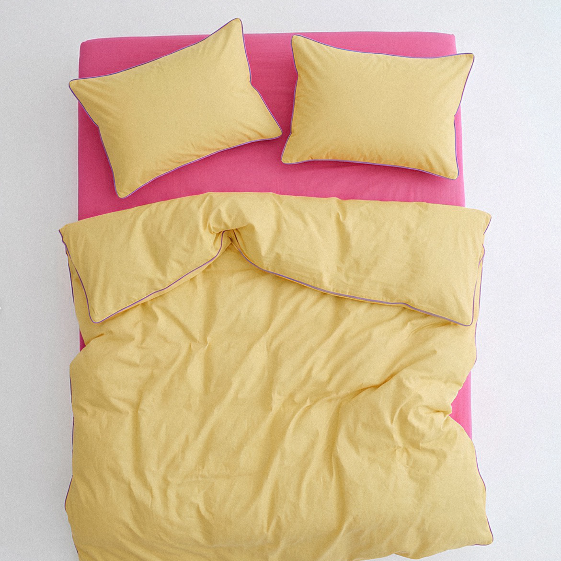 Yellow bedding set with pink bed frame on a white background