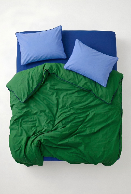 Green comforter and blue pillows on a bed against a white background
