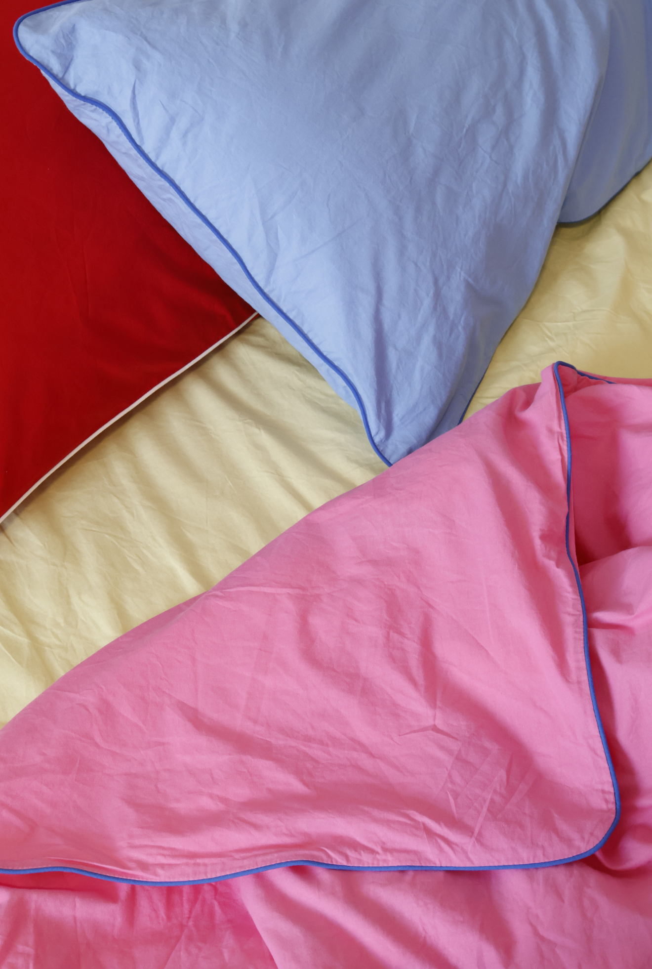 Close-up of a pink blanket with blue trim on a bed.