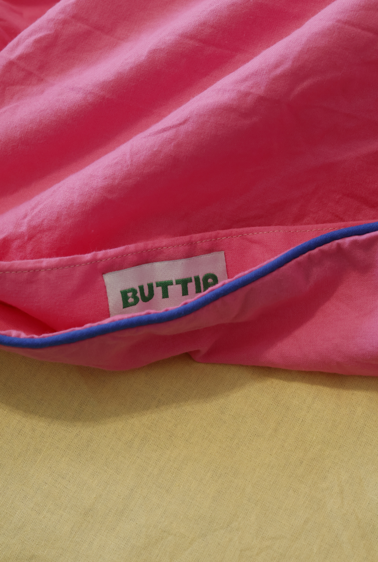 Close-up of a pink product with a 'BUTTIA' label on a yellow background