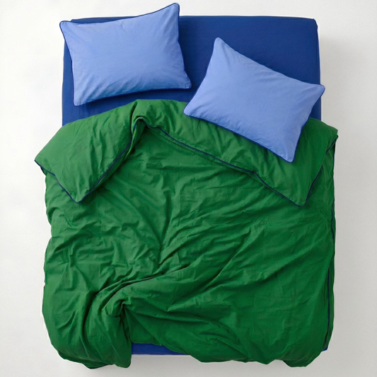 Green comforter and blue pillows on a bed with a white background