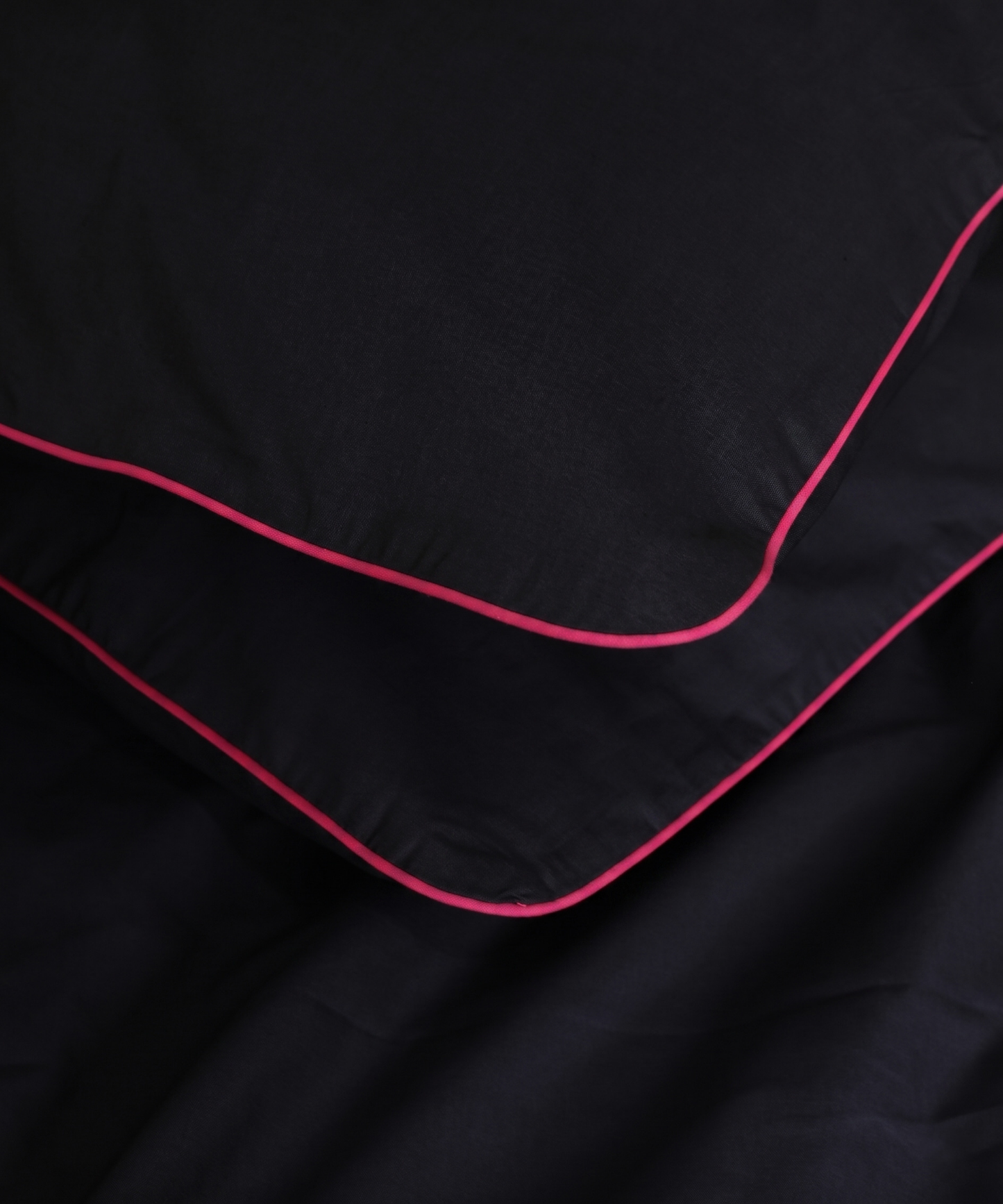 Black pillows corners with pink piping on a dark background