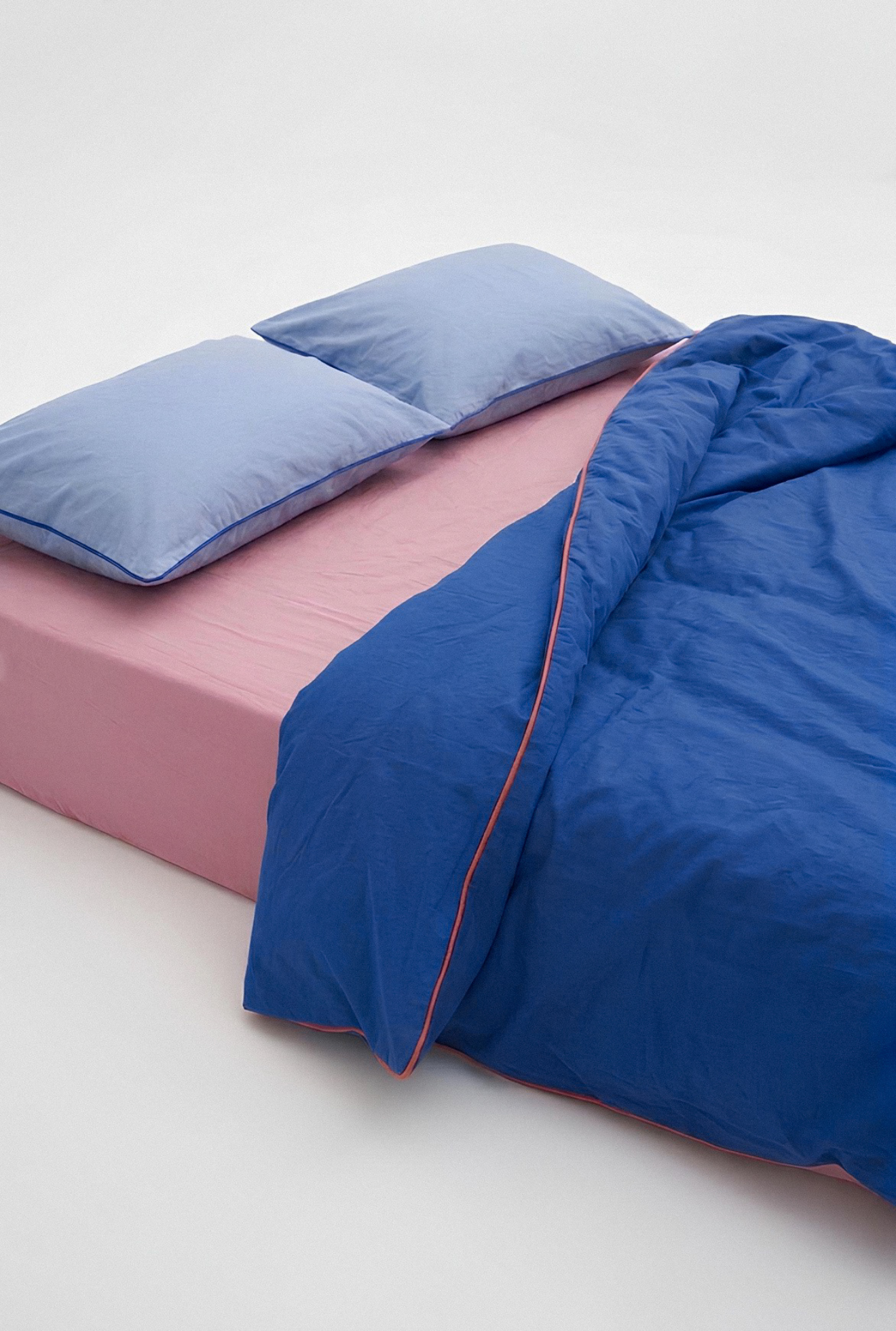 Blue bedding set on a pink bed with a white background