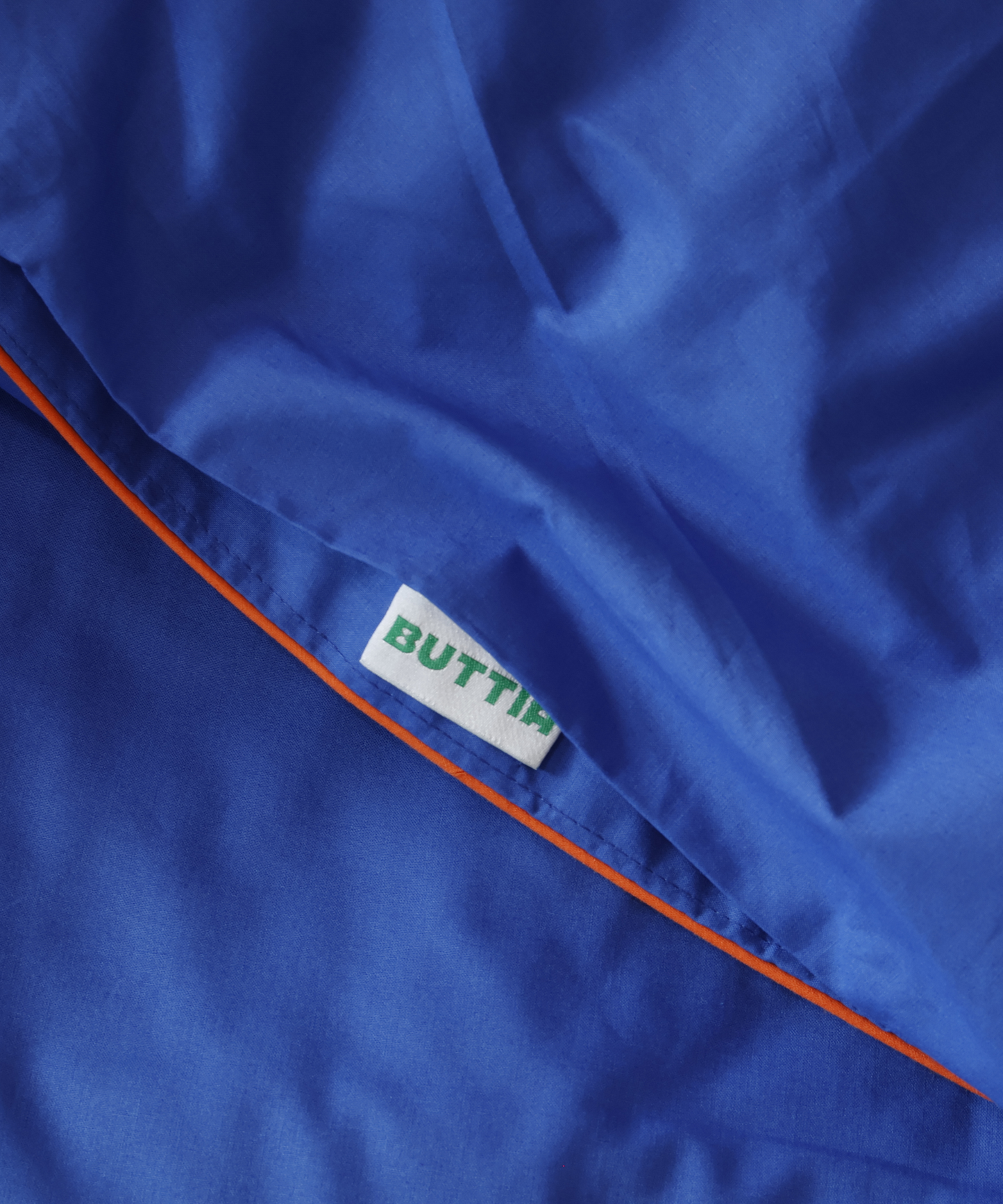 Close-up of a blue fabric with a 'BUTTIA' label.