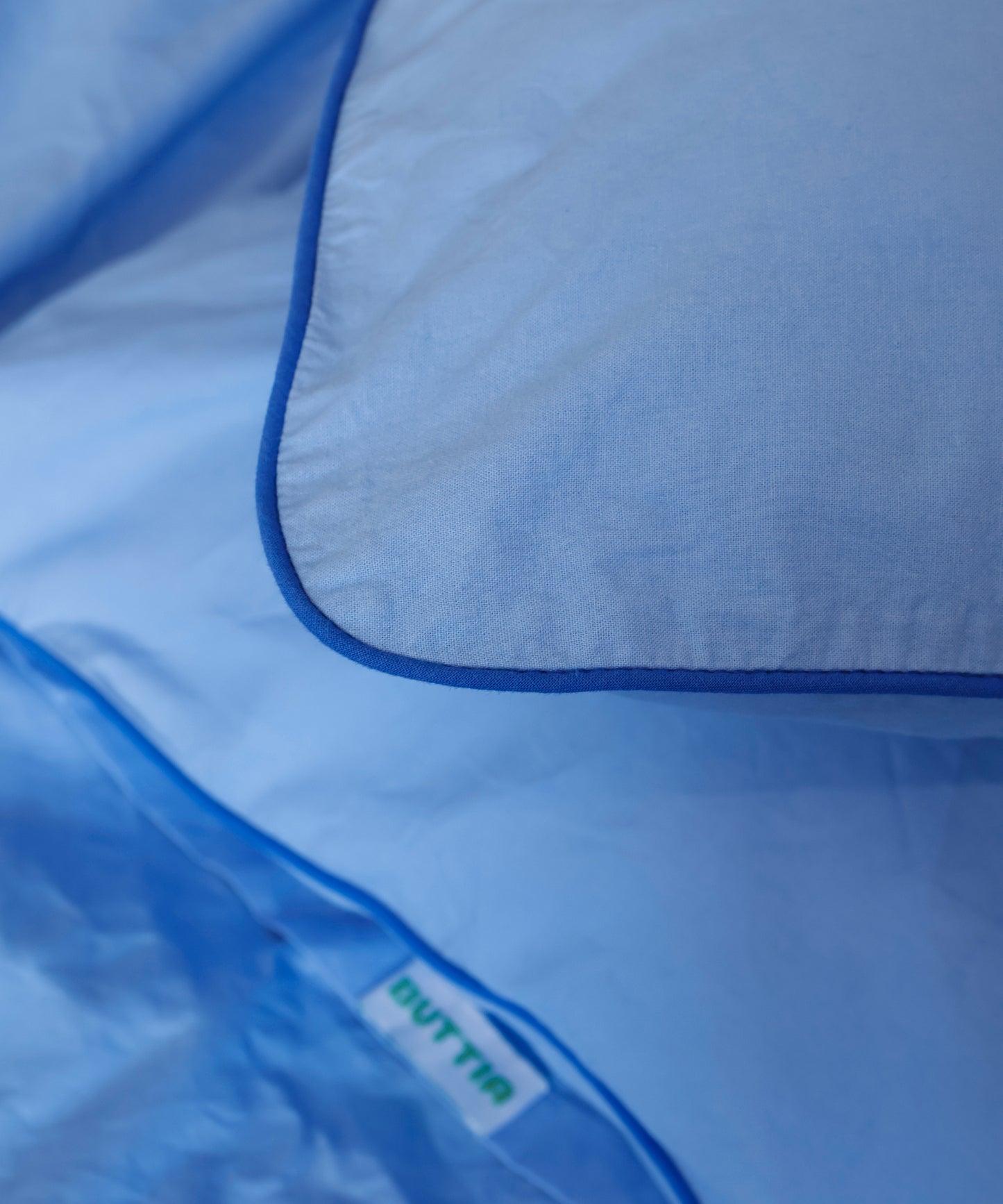 Close-up of a blue garment bag with 'BUTTIA' branding.
