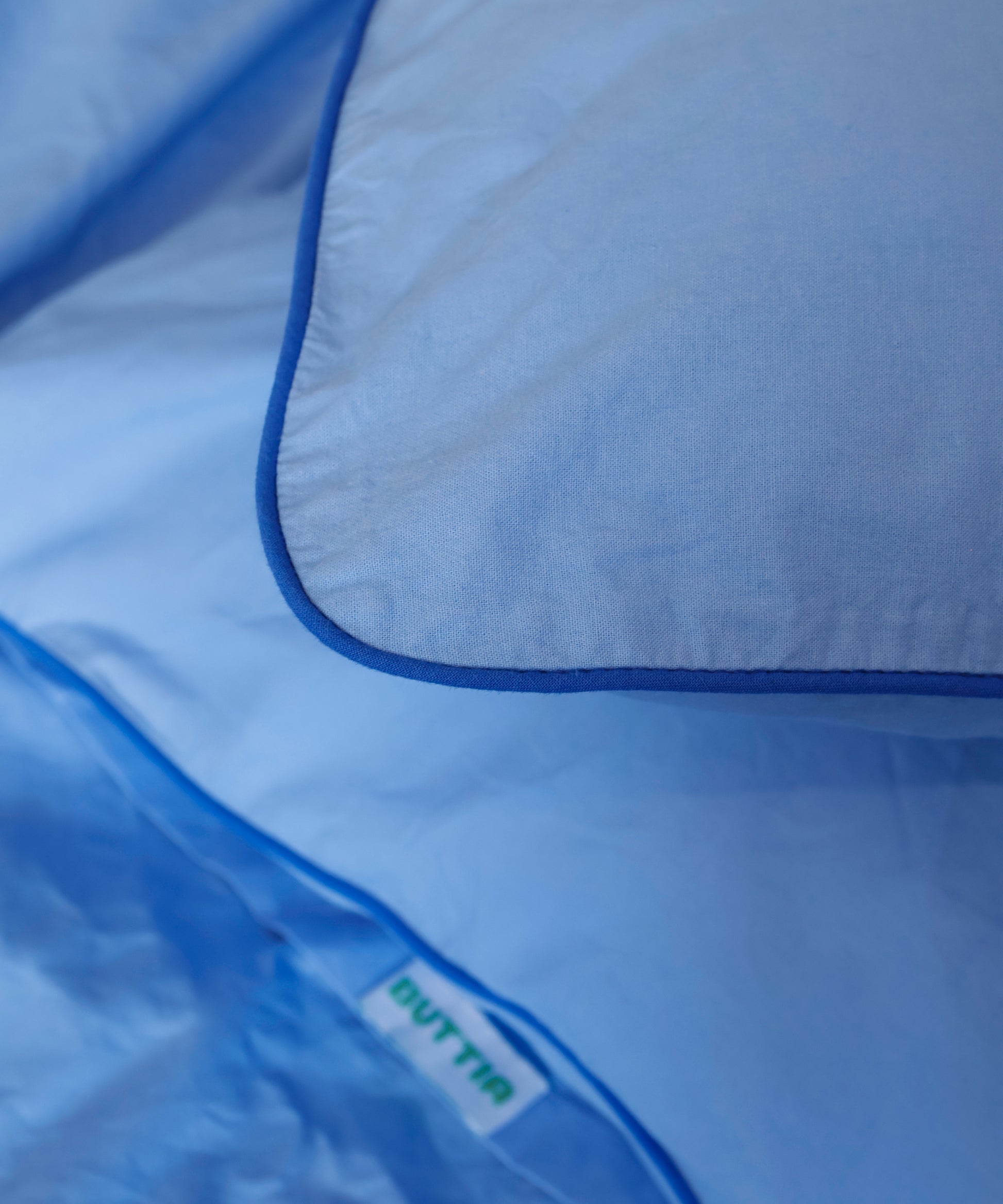 Close-up of a blue garment bag with 'BUTTIA' branding.