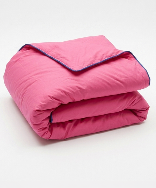 A folded hot pink quilted comforter with a contrasting dark blue piping trim, shown on a clean white background.