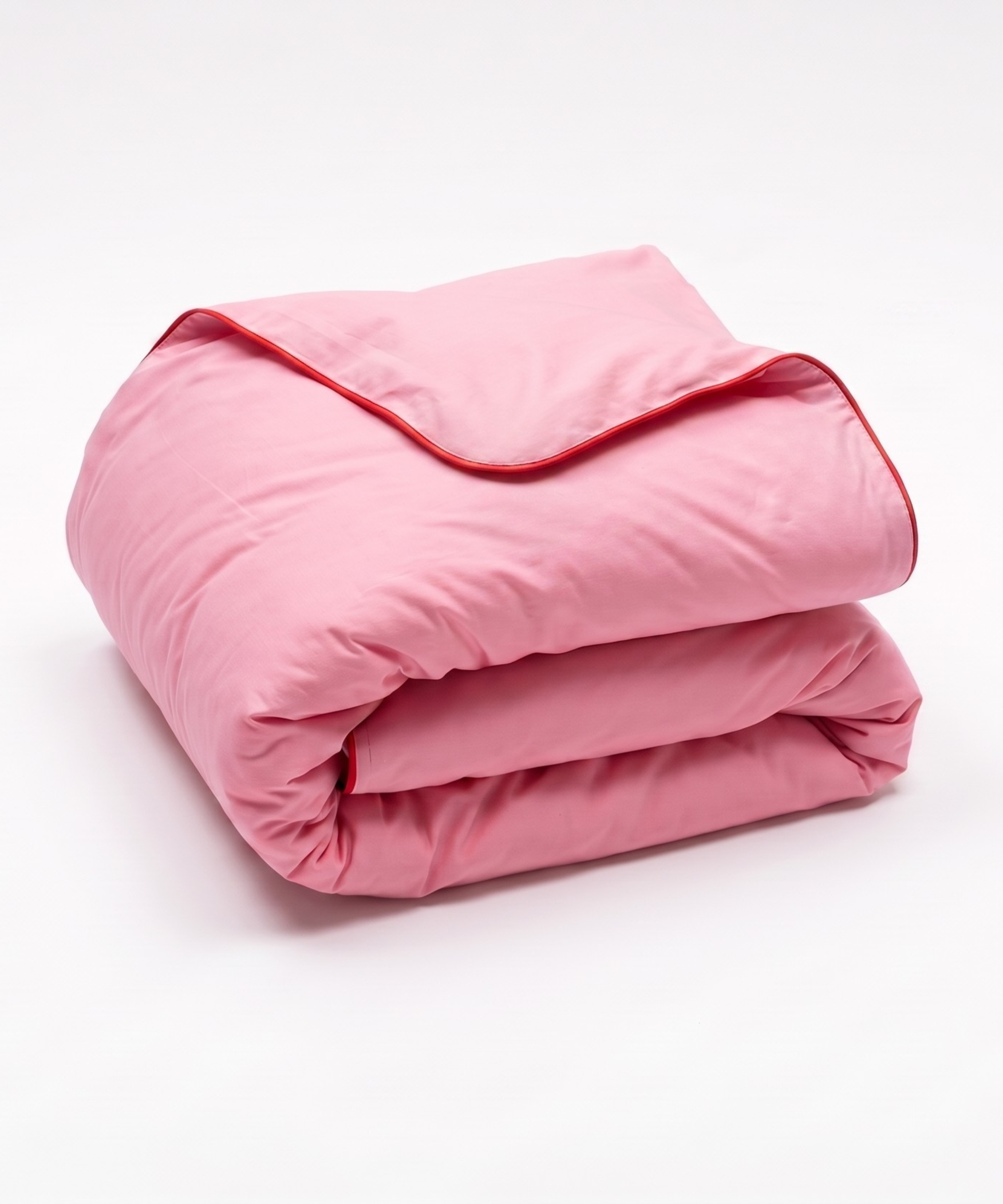 A folded pink quilted comforter with contrasting red piping, shown on a clean white background.