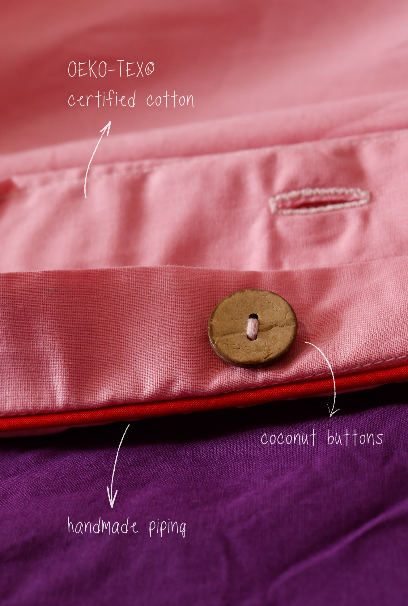 Close-up of pink fabric with coconut buttons and text indicating OEKO-TEX certified cotton and handmade piping.
