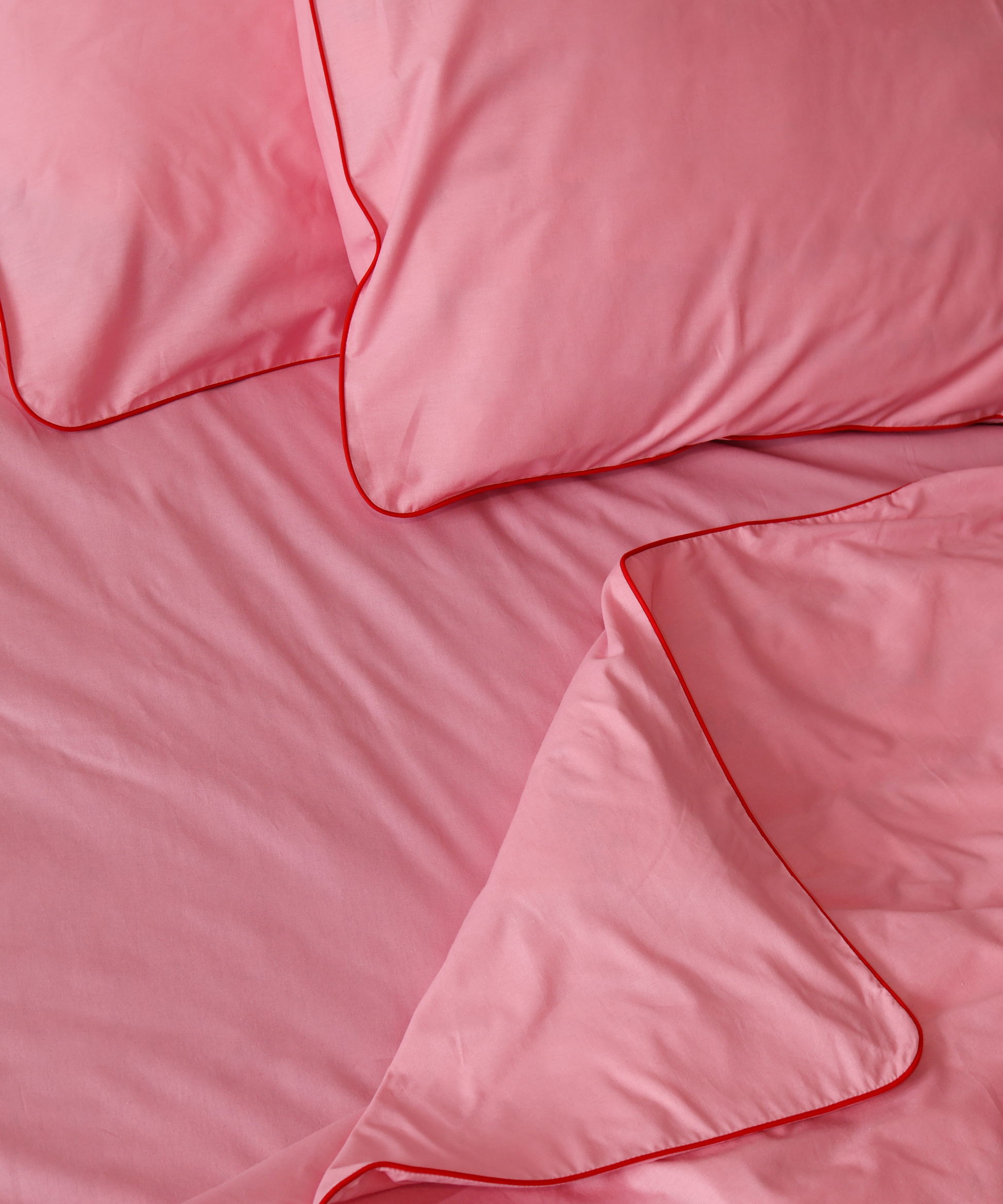 Pink bedding set with duvet and pillows on a plain background