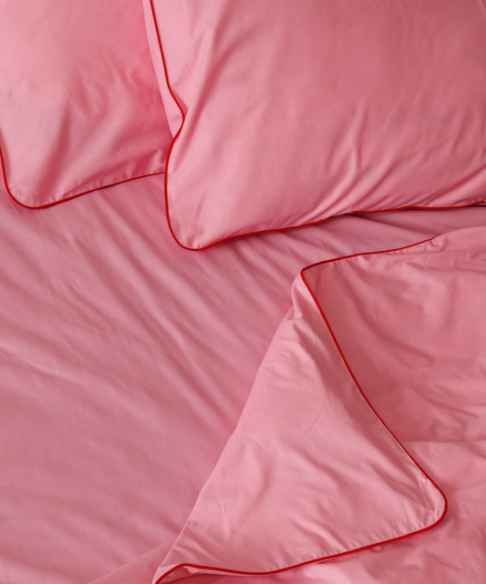 Pink bedding set with duvet and pillows on a plain background