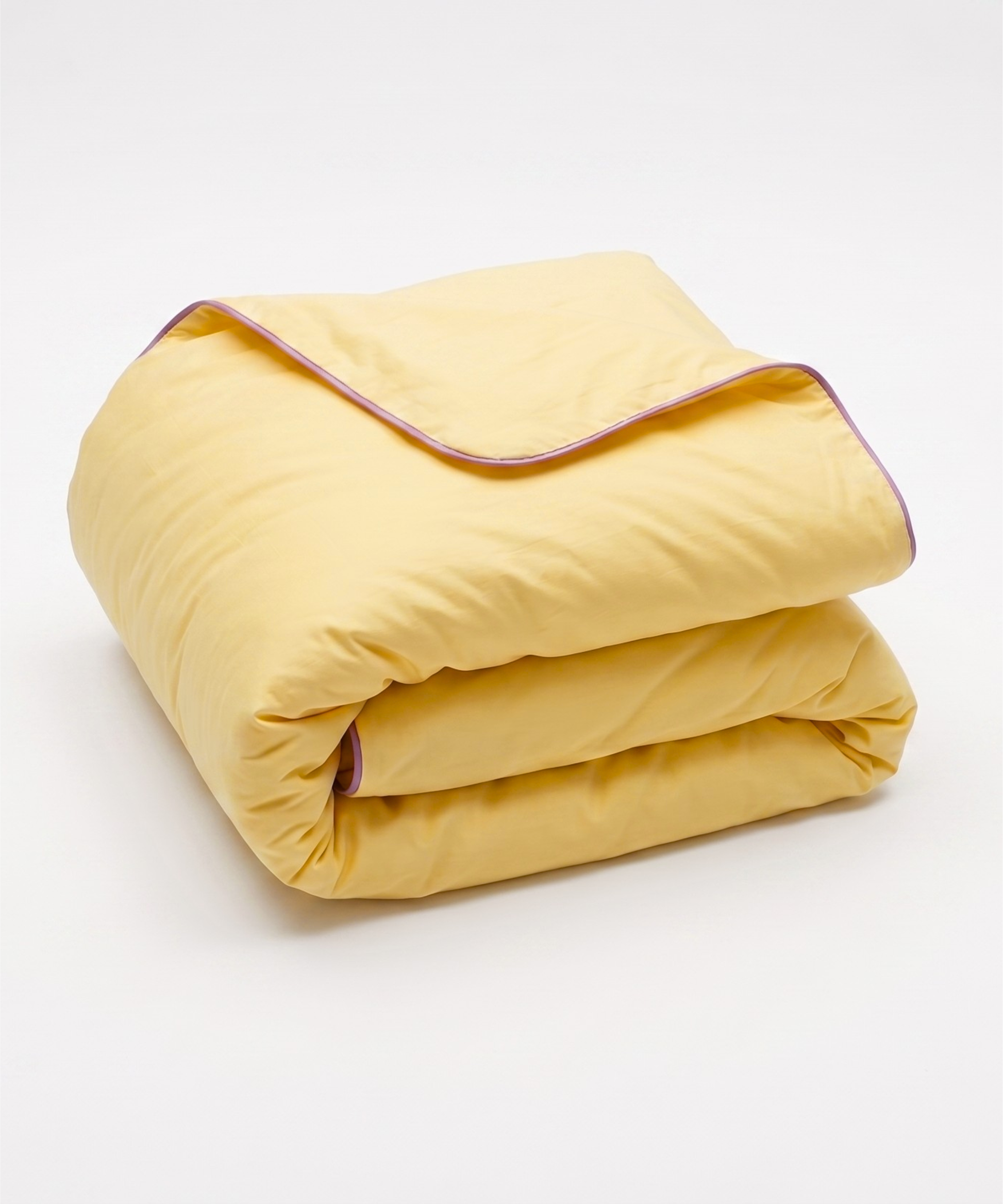 A folded yellow quilted comforter with a thin purple piping trim, shown on a clean white background.
