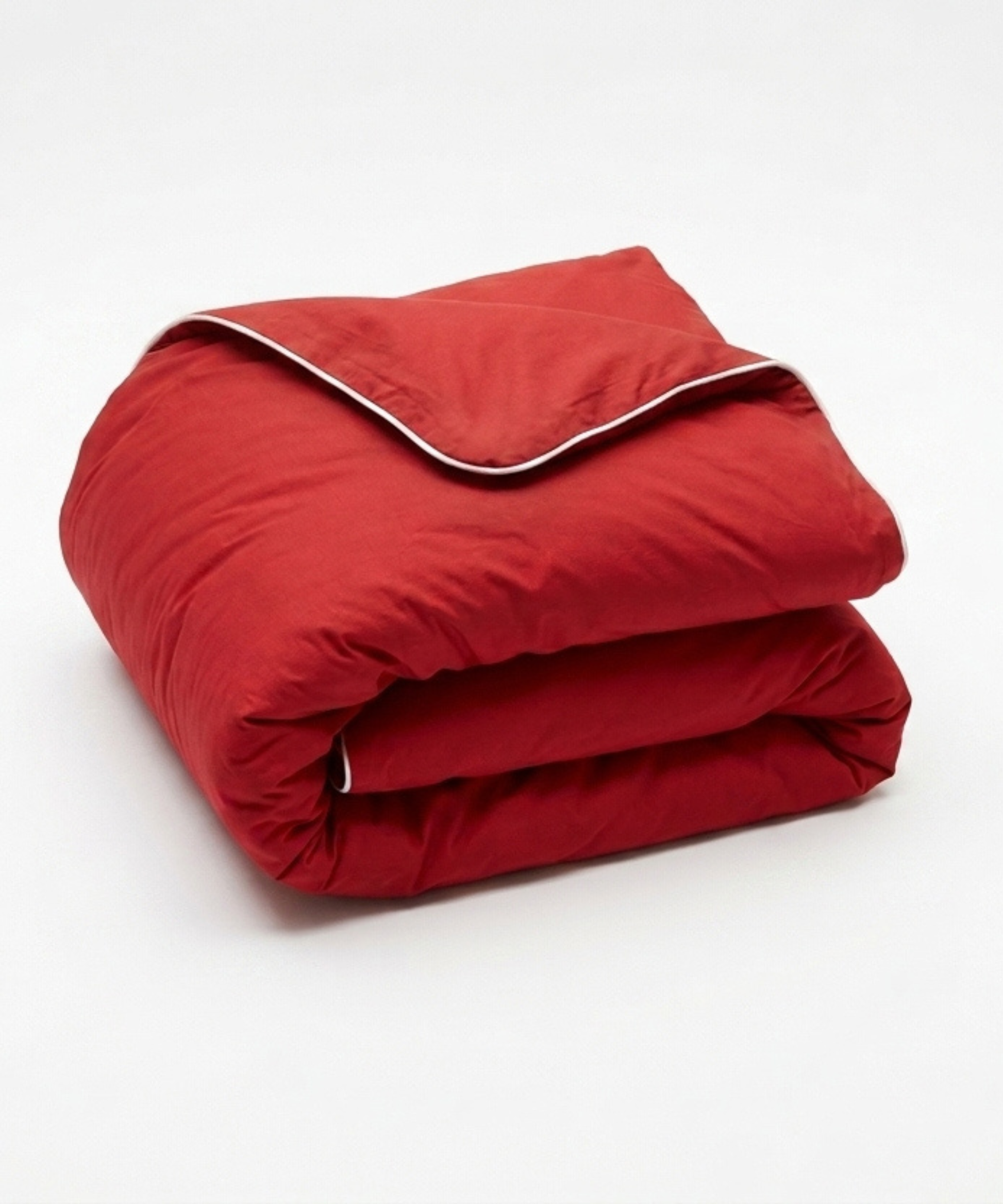 A folded red comforter or duvet with a white piping trim along the edge, shown on a clean white background.