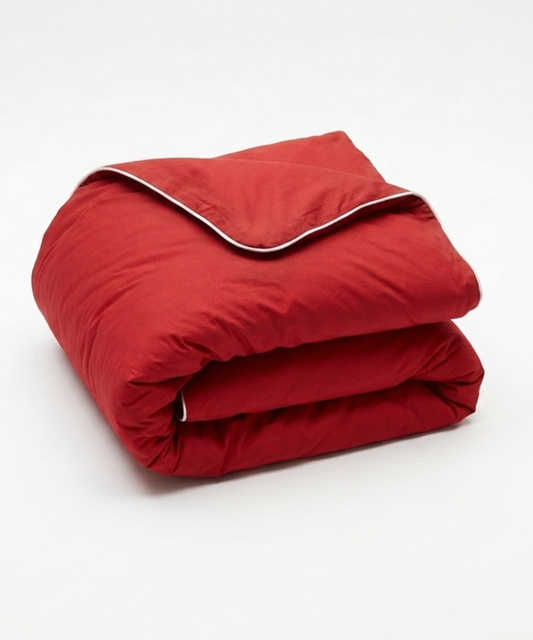 A folded red comforter or duvet with a white piping trim along the edge, shown on a clean white background.