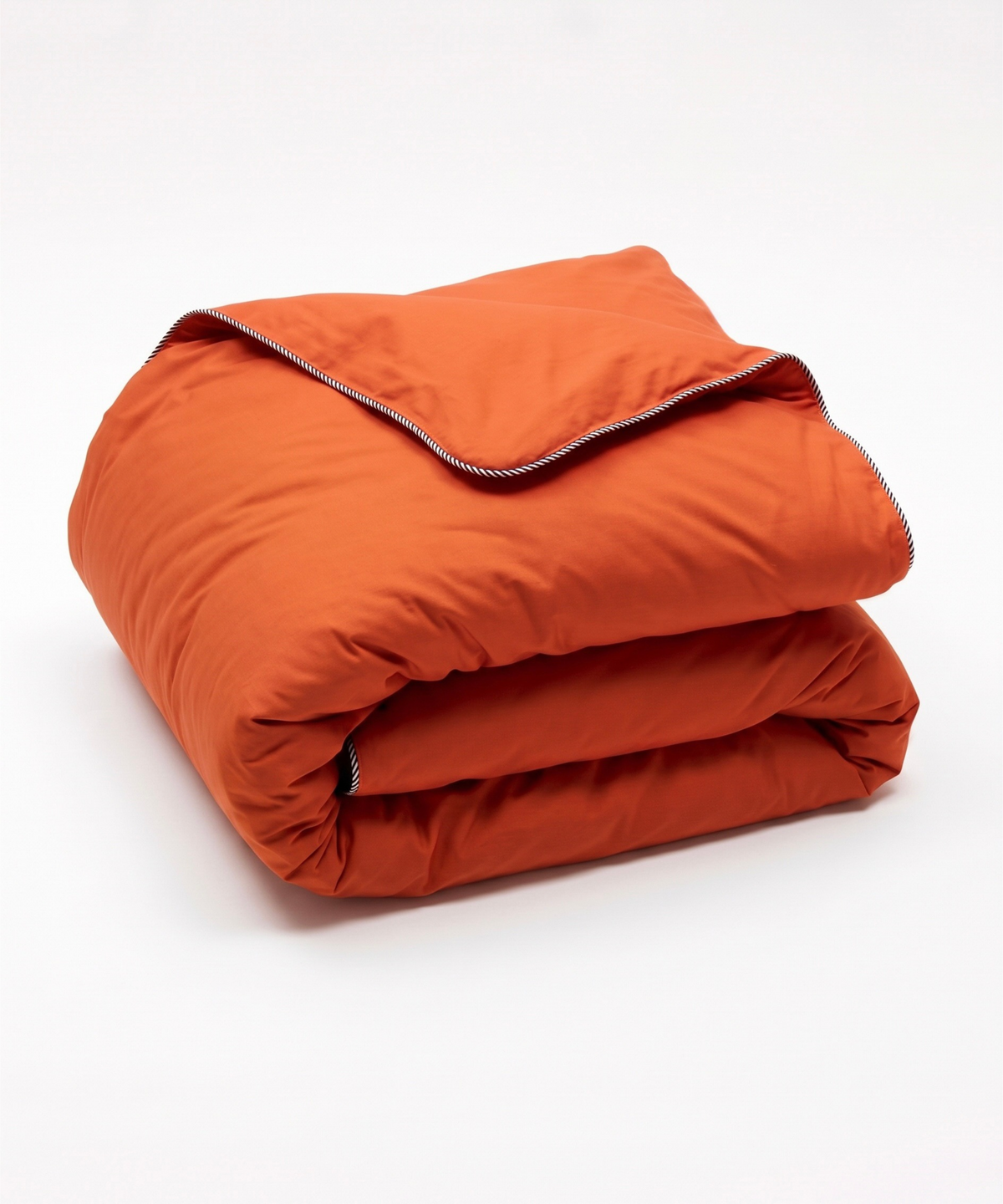 A folded orange quilted comforter or duvet with a visible stripe trim, photographed on a clean white studio background.