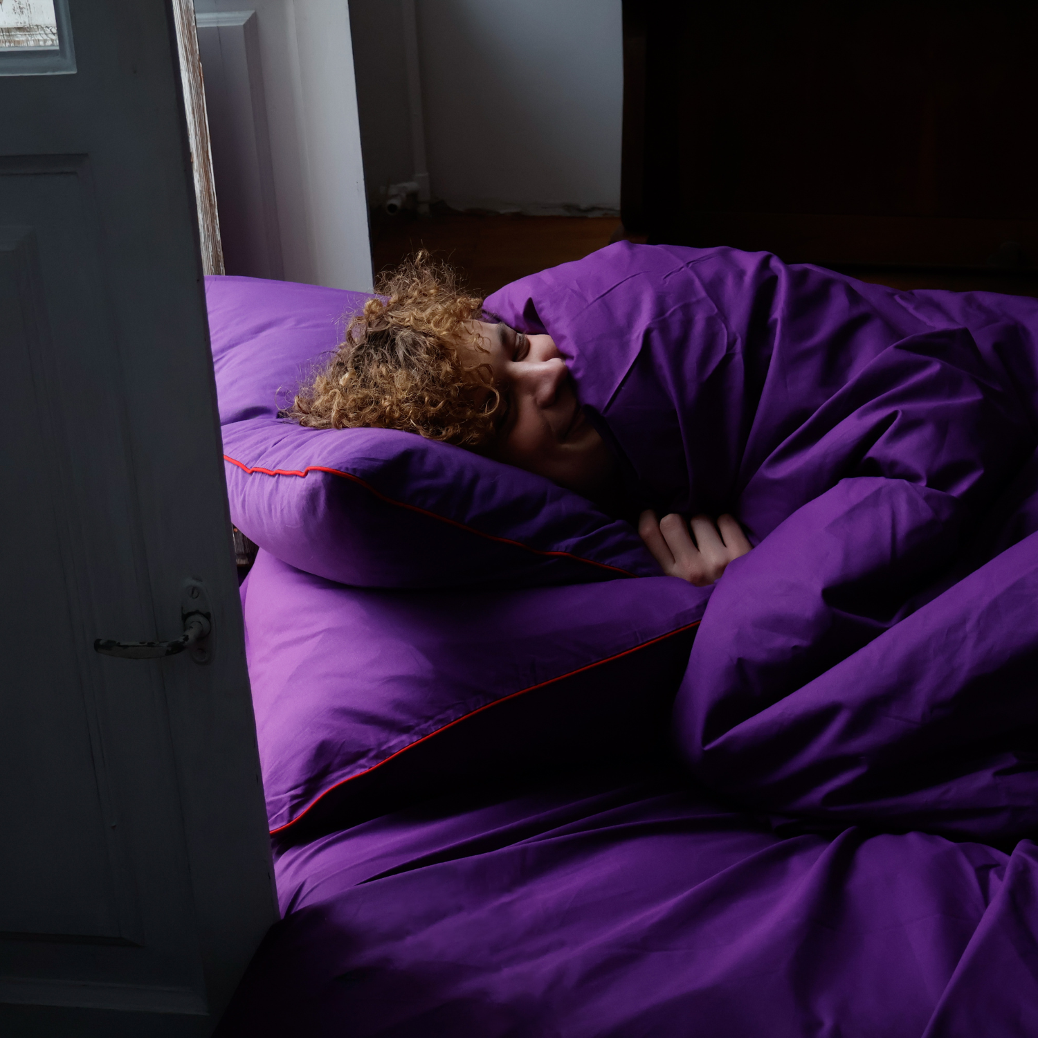 Feeling of comfort with a guy wrapped in a BUTTIA bedding set with red piping.