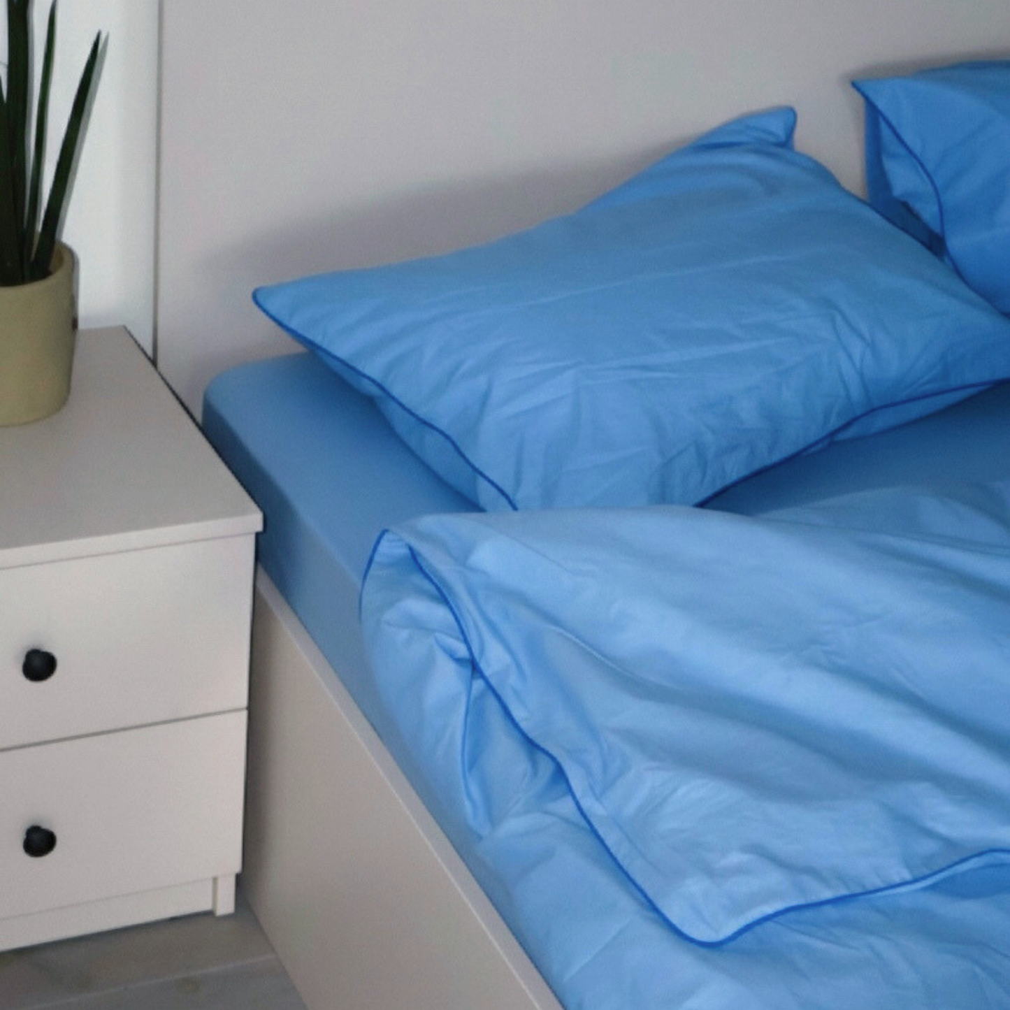 BUTTIA premium light blue bed linen made of natural fabric with decorative blue edge finish.