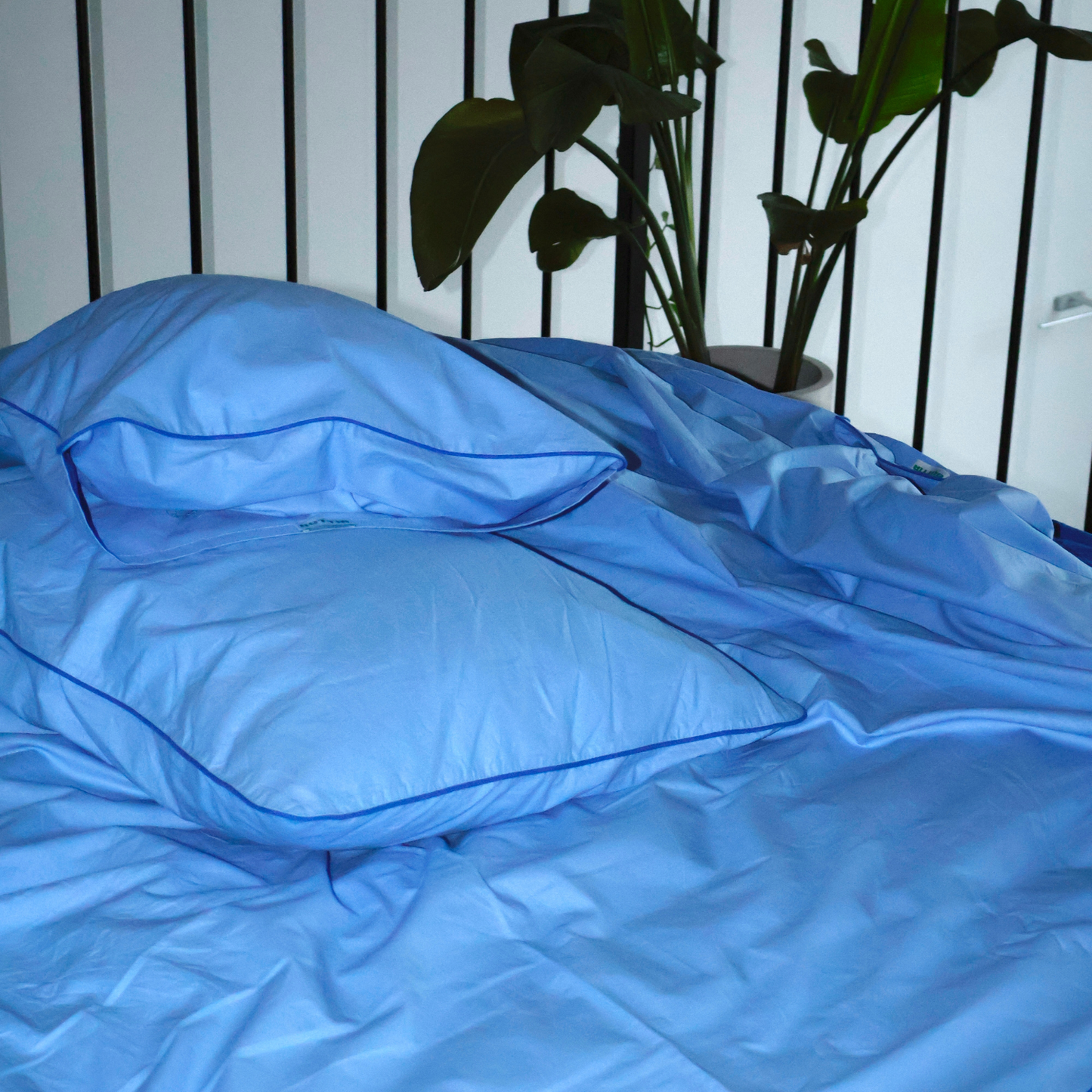 Close-up of BUTTIA blue pillowcase with elegant navy piping detail and natural cotton texture.